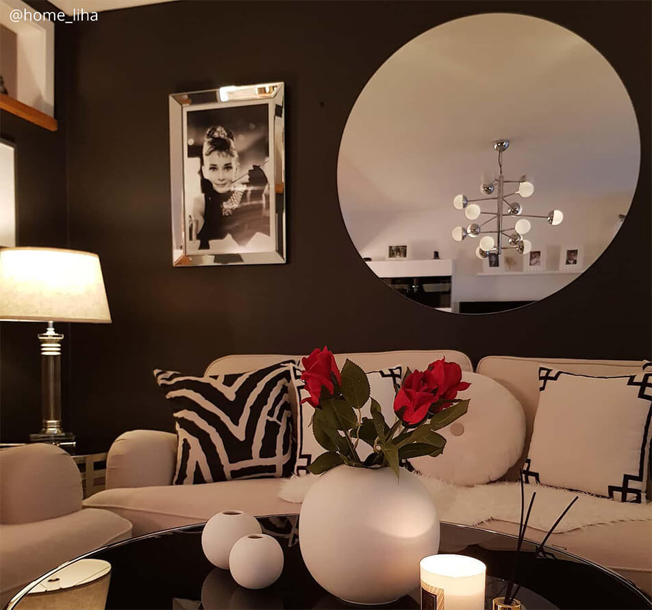Salon avec couleur de mur sombre, canap blanc et grand miroir rond